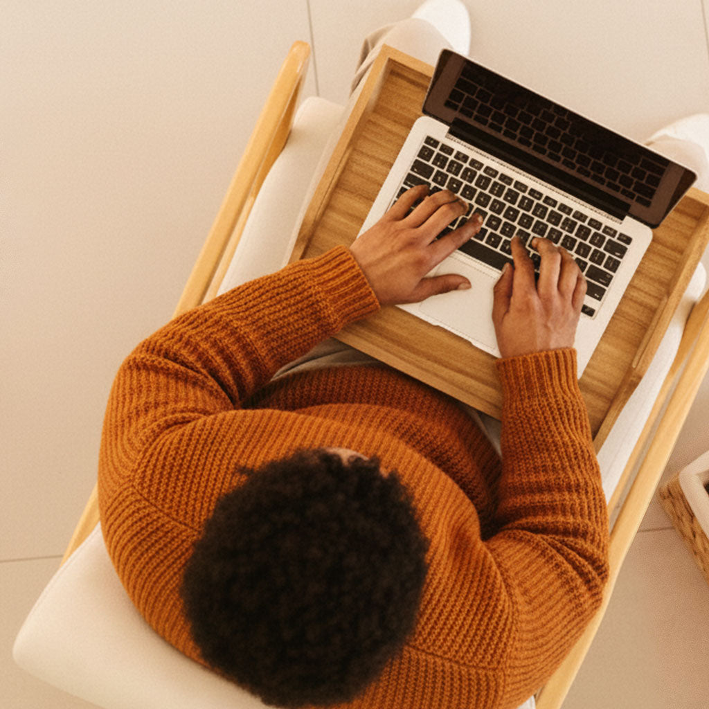 Person using a laptop on a wooden stand with a blurred background